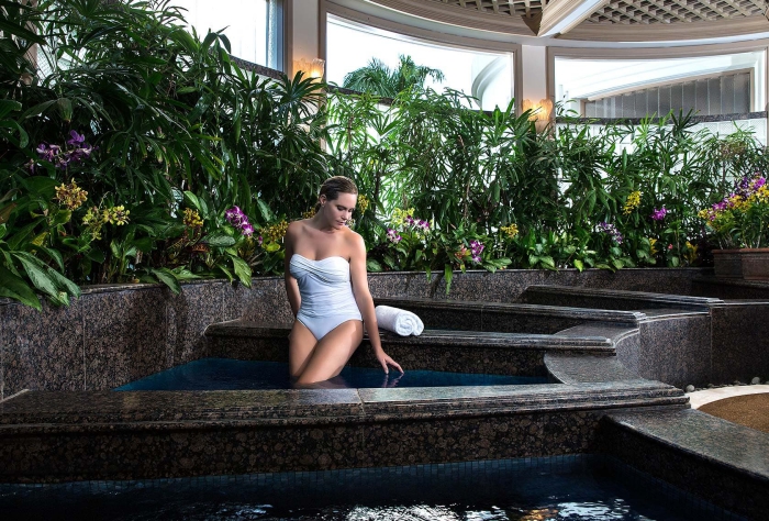 luxury hotel spa wellness area woman in a water bath surrounded by greenery 