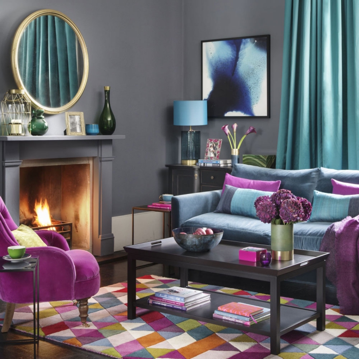 Grey living room with bright colorful accents purple chair blue curtains and a fireplace