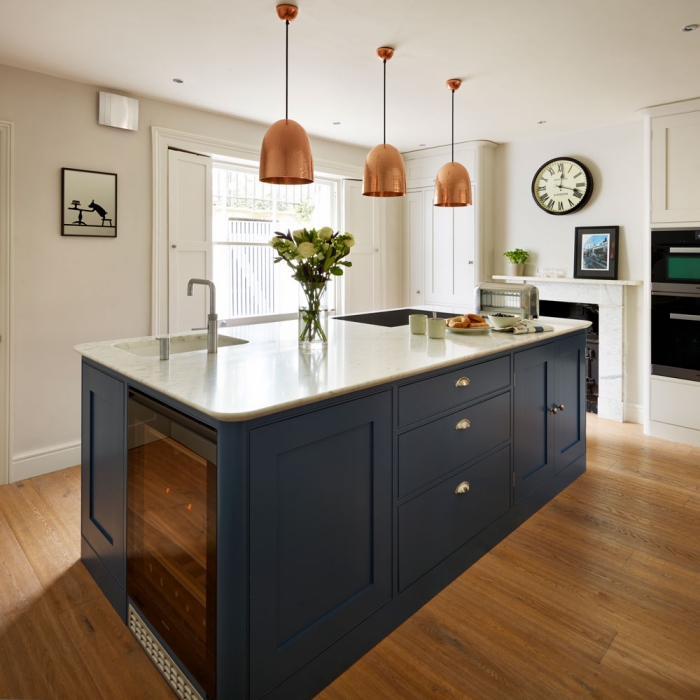 White kitchen interior with dark grey kitchen island and copper pendant lamps