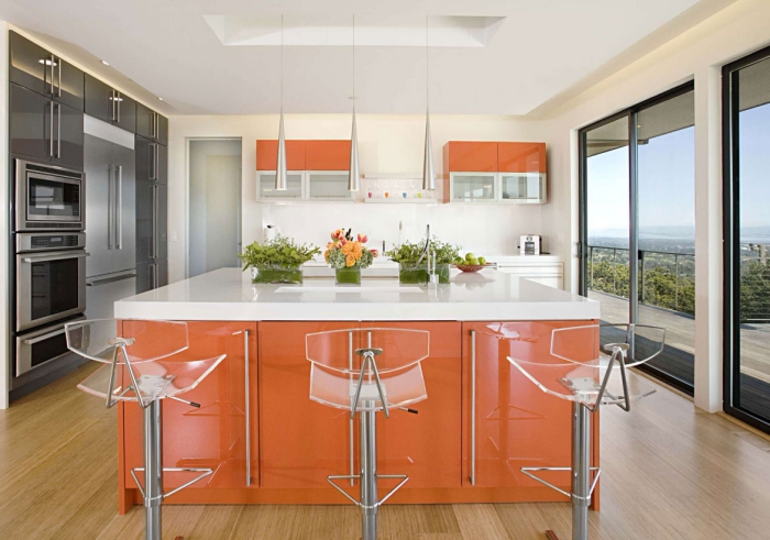 Modern kitchen in white and orange with transparent chairs and large windows