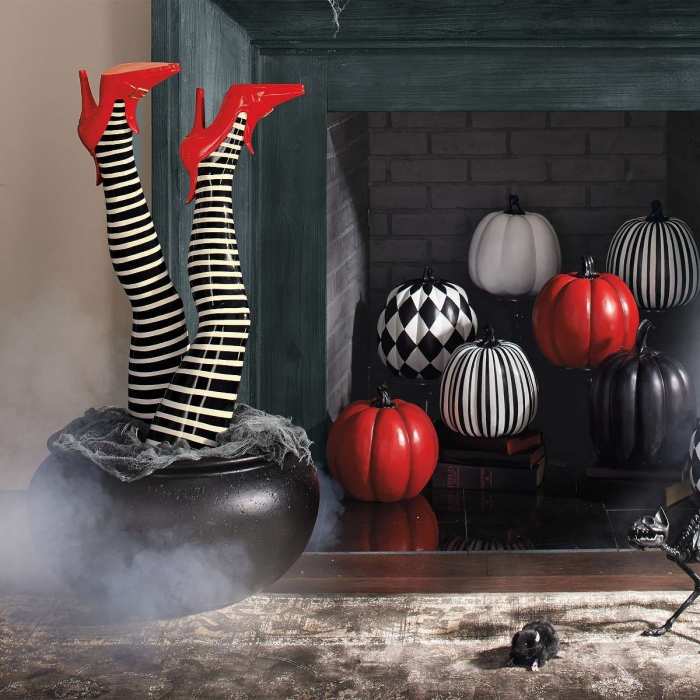 Indoor Halloween decor with colorful pumpkins in a fireplace and legs in a pot