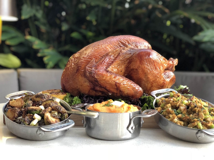 Thanksgiving turkey with different side dishes on a table with greenery in the background