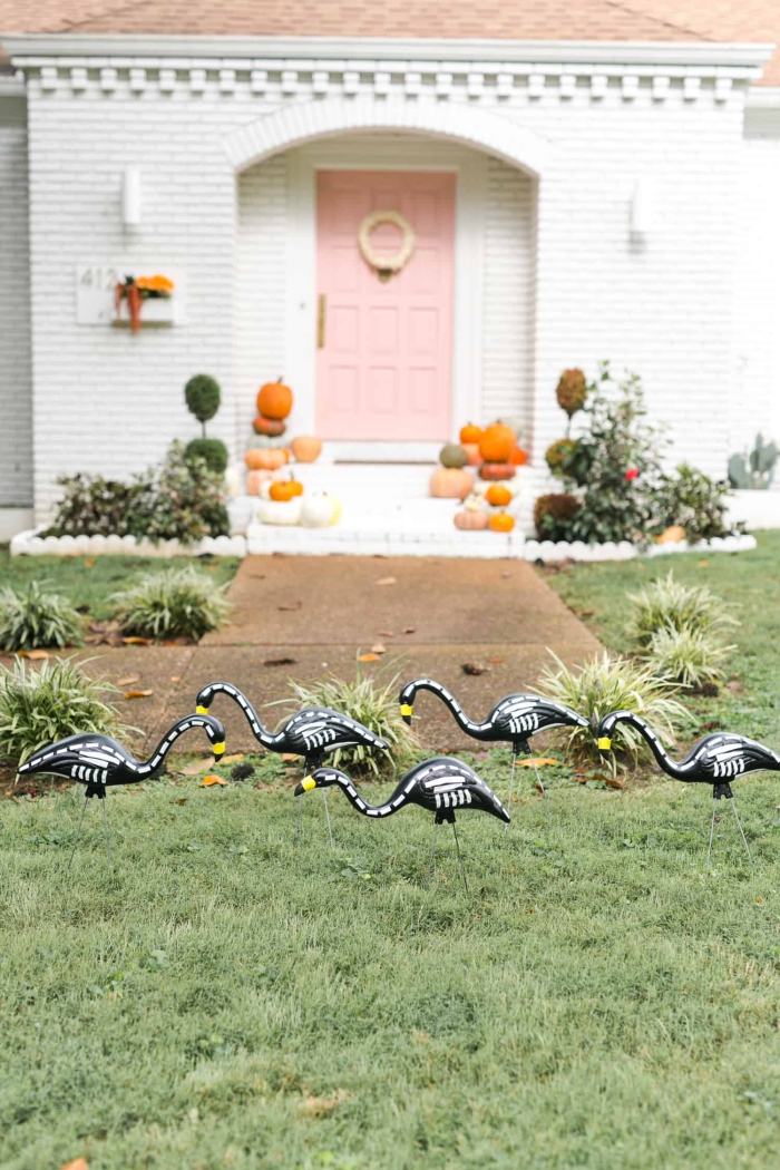 Skeleton Flamingos in a front yard white and pink door in the background