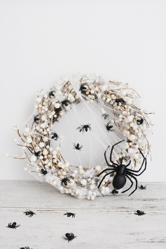 White spider web Halloween door wreath with a black spider and flies