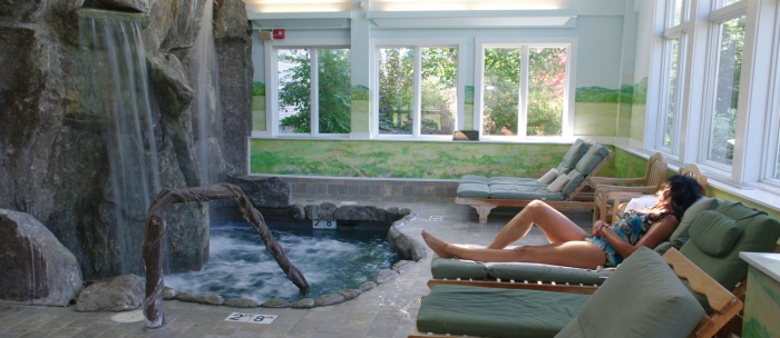 woman relaxing at an indoor spa area with stone indoor waterfall