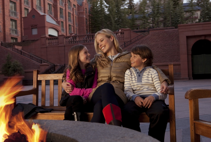 Mom sitting with children boy and girl in front of the outdoor fire 