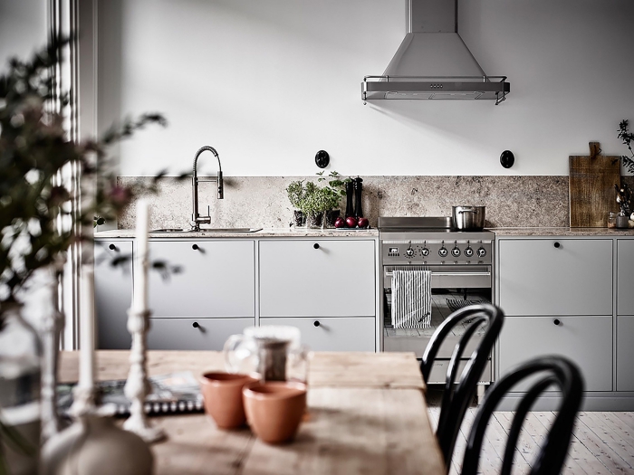 Small white one-unit kitchen with black chairs and metallic surfaces