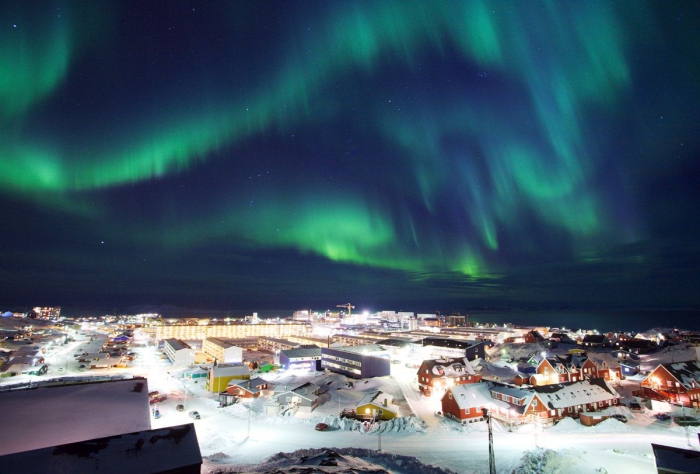 Northern lights over Greenland night sky with aurora over snowy town landscape