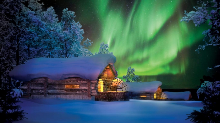 Northern lights in the winter night sky wooden houses with glass roof covered terrace