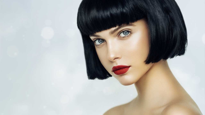 woman with pale skin black hair blue eyes and red lips on a light background