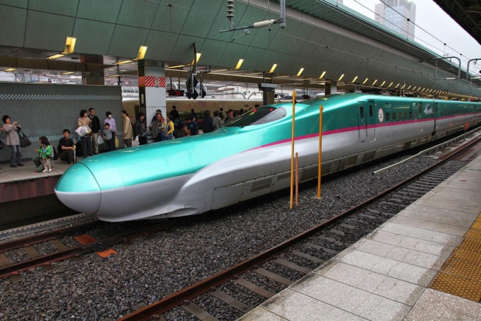 Japan bullet train in green and white at a station 