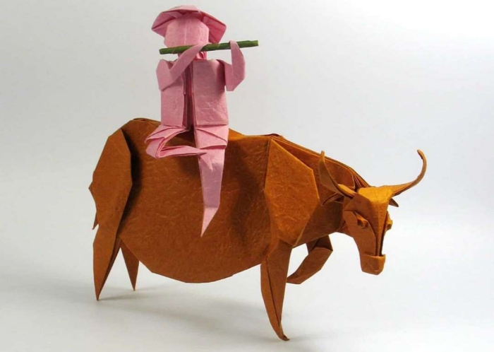 Japanese Origami orange bull with pink paper man playing with whistle