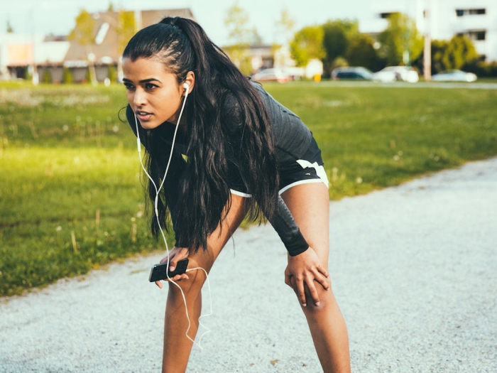 Woman jogging in black shorts and headphones and phone