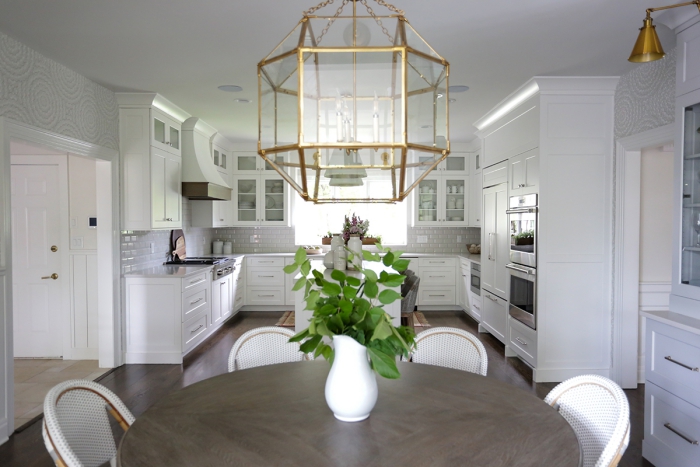 sophisticated white kitchen and dining area with metal and glass lighting fixture