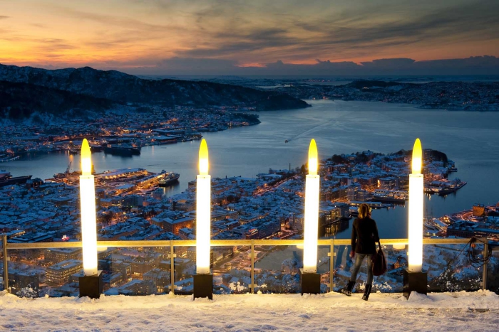 Woman standing on a decorated terrace overlooking Bergen in the evening