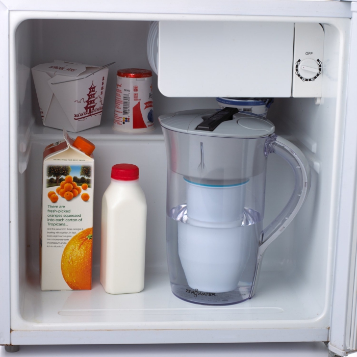 Water jug inside a fridge next to juice box and bottle