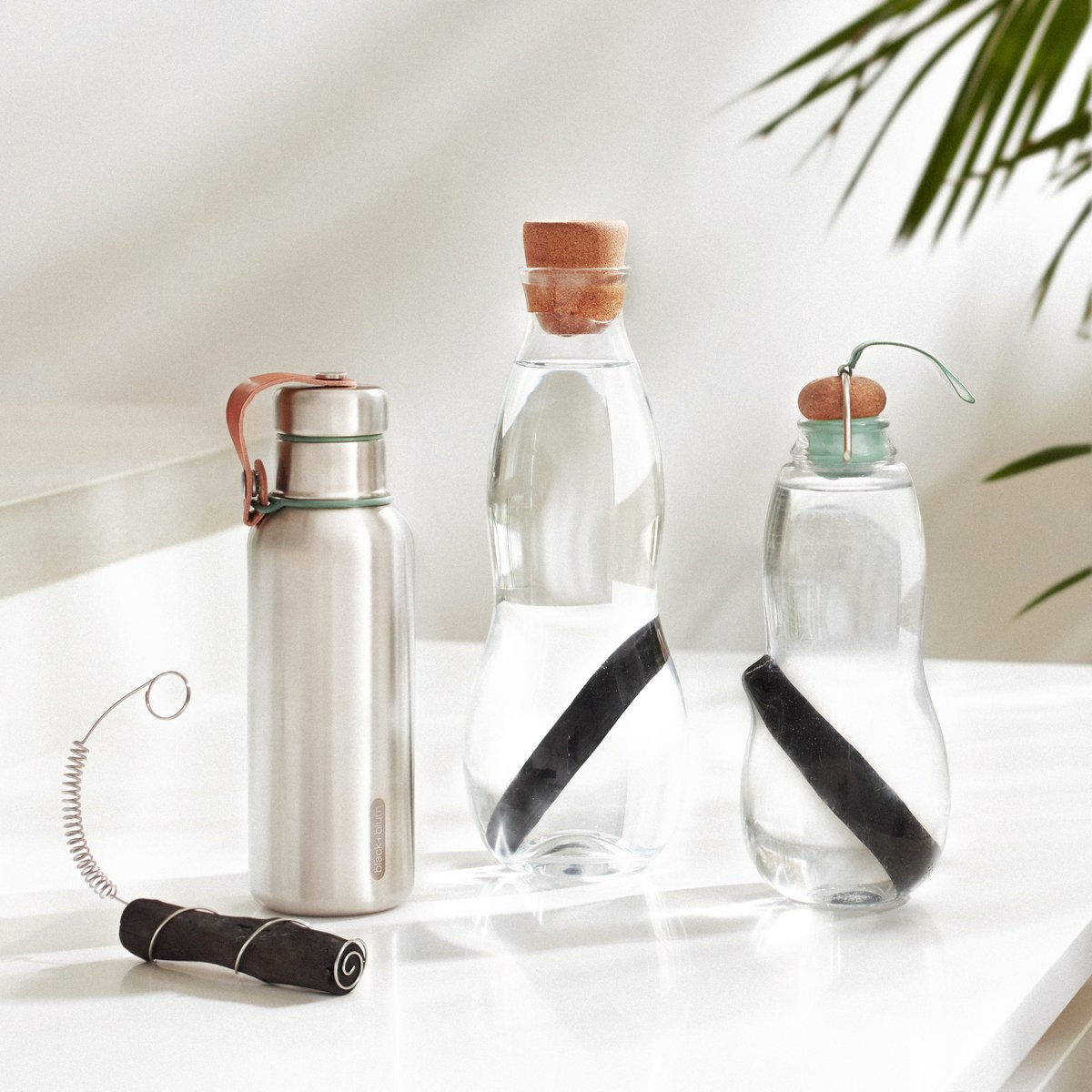 Three water jugs two glass one metal on a white table