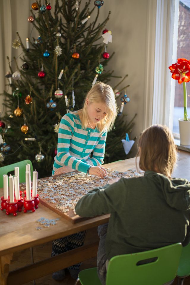 two girls playing board games at home Christmas tree in the background