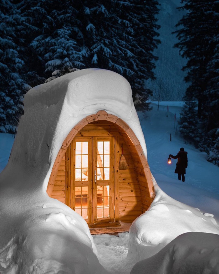 Christmas getaway in the woods cabin covered in snow woman with a lantern walking in background