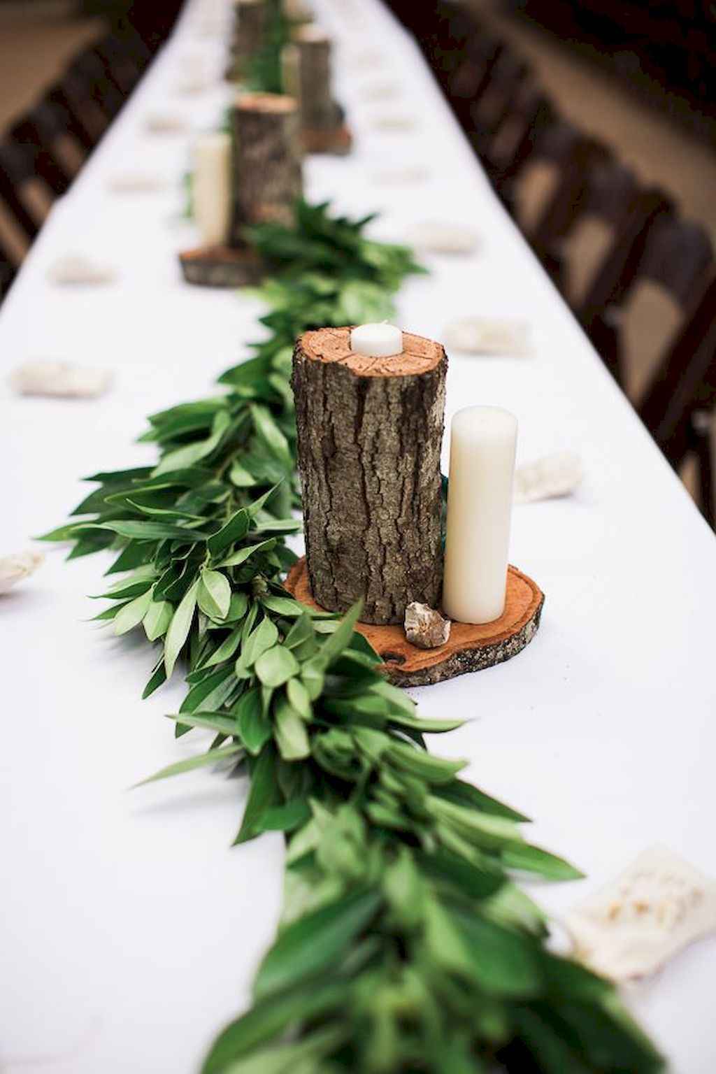 Green table centerpiece long table with tree log candle holders and branches white table cloth