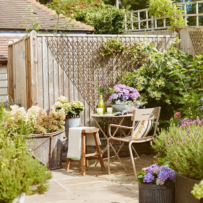 Small patio area with a table and chair surrounded by plants and greenery