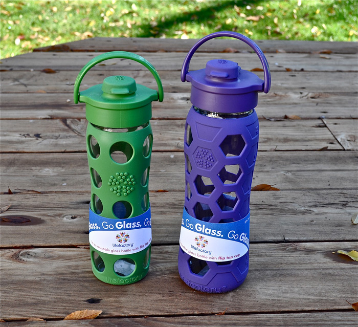 two water bottles with green and purple silicone sleeve outdoor 