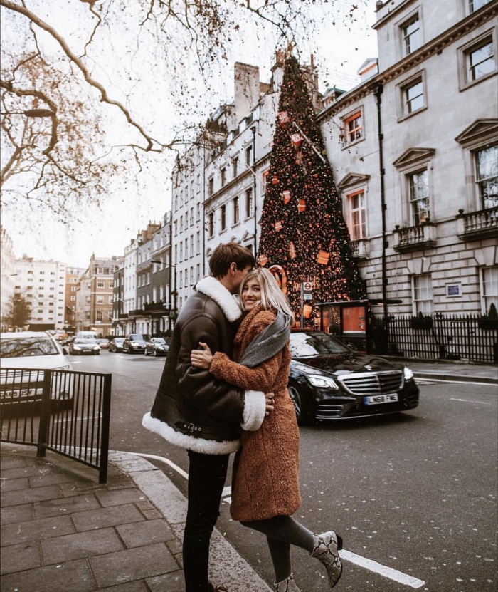 Couple hugging in front of large christmas tree in london 