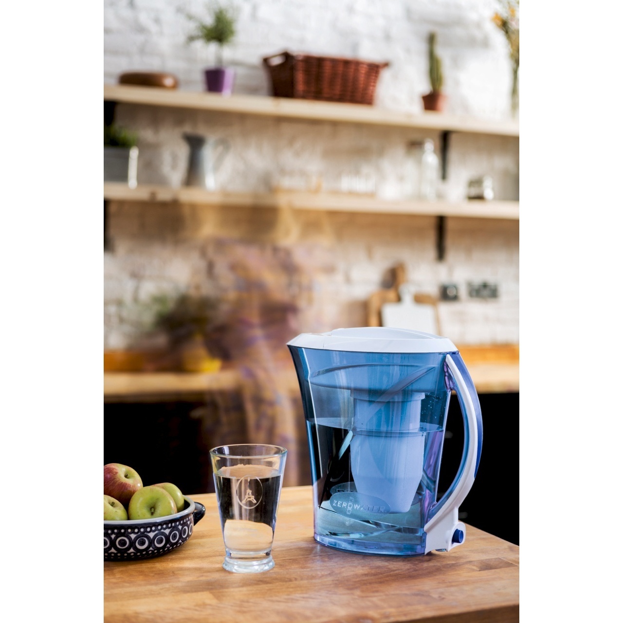 Light blue water filter jug on a table with glass kitchen background