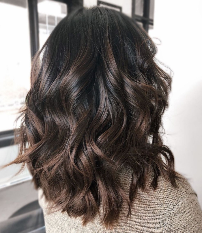 Chocolate balayage with highlights woman back middle length hair waves