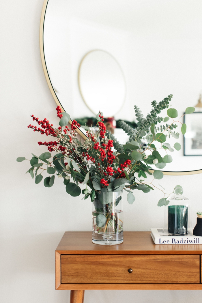 Christmas trends flower decor green and red arrangement in a glass vase in front of a mirror