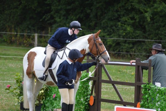 two horse riders a horse outdoors in a stable