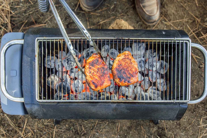 Person grilling two pieces of cheese on an outdoor grill