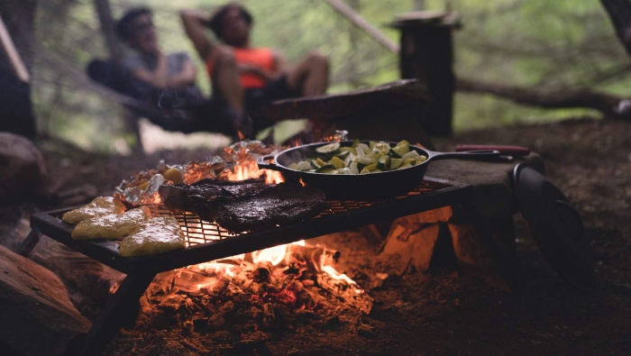 two people sitting in the background grilled dinner fire camping