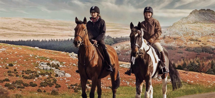 Devon horse riding in UK two women riding horses in the countryside