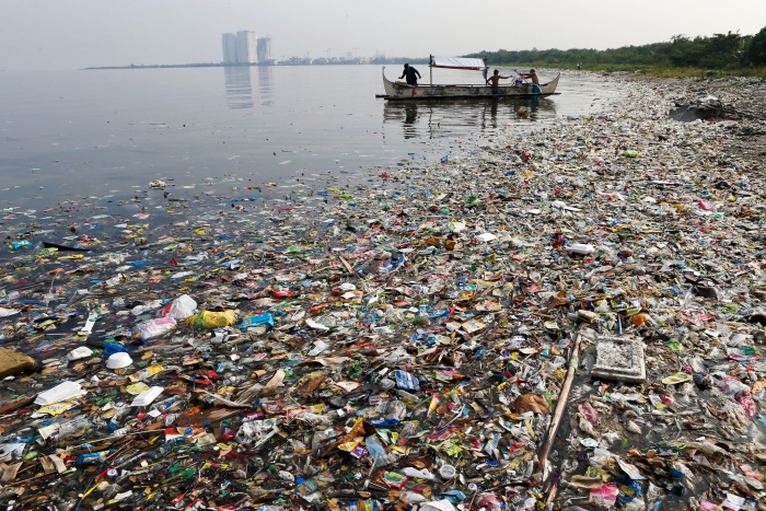 Plastic beach litter worldwide sea with a lot of litter boat with people tall buildings