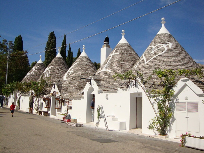 street with trullo houses people on the street white houses trulli Italy Puglia