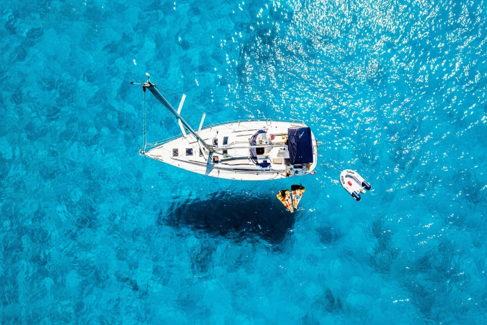 Boat in the middle of clear blue water people swimming