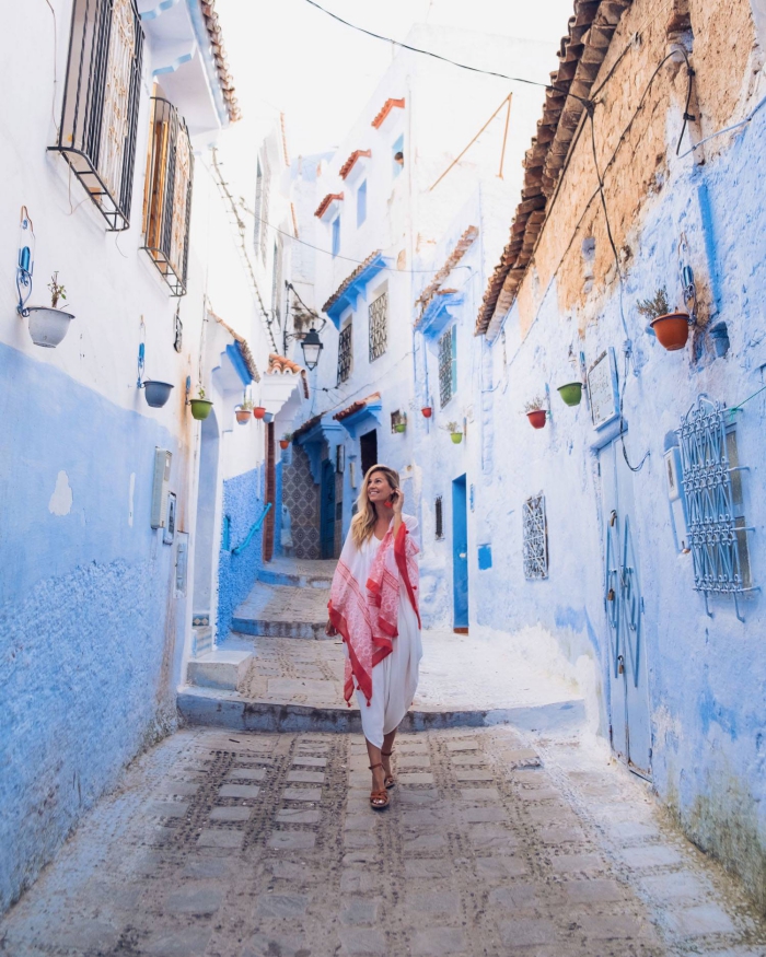 woman with a red scarf in a beautiful setting white and blue brick houses