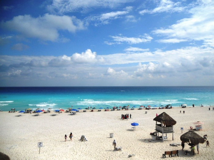 Playa Delfines white sand wide beach umbrellas people sunbathing