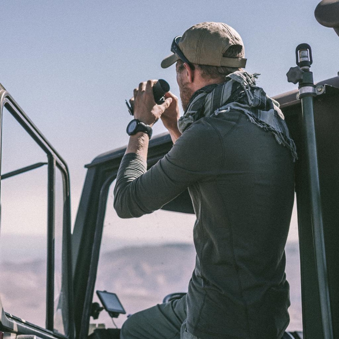 man with shemagh in an off road drive watching with binoculars 