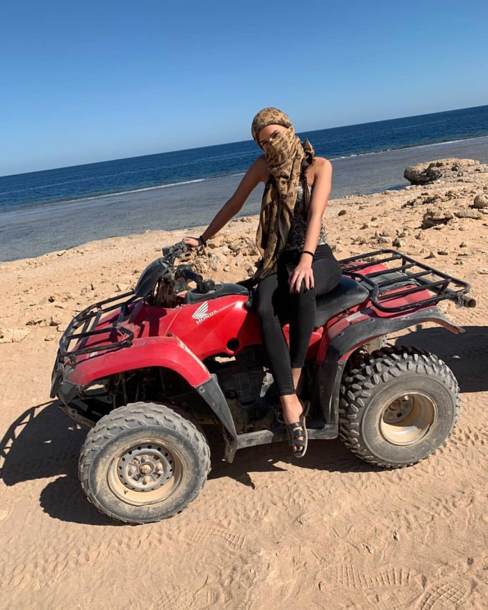 Travel with shemagh woman on ATV with a shemagh around her head beach red atv