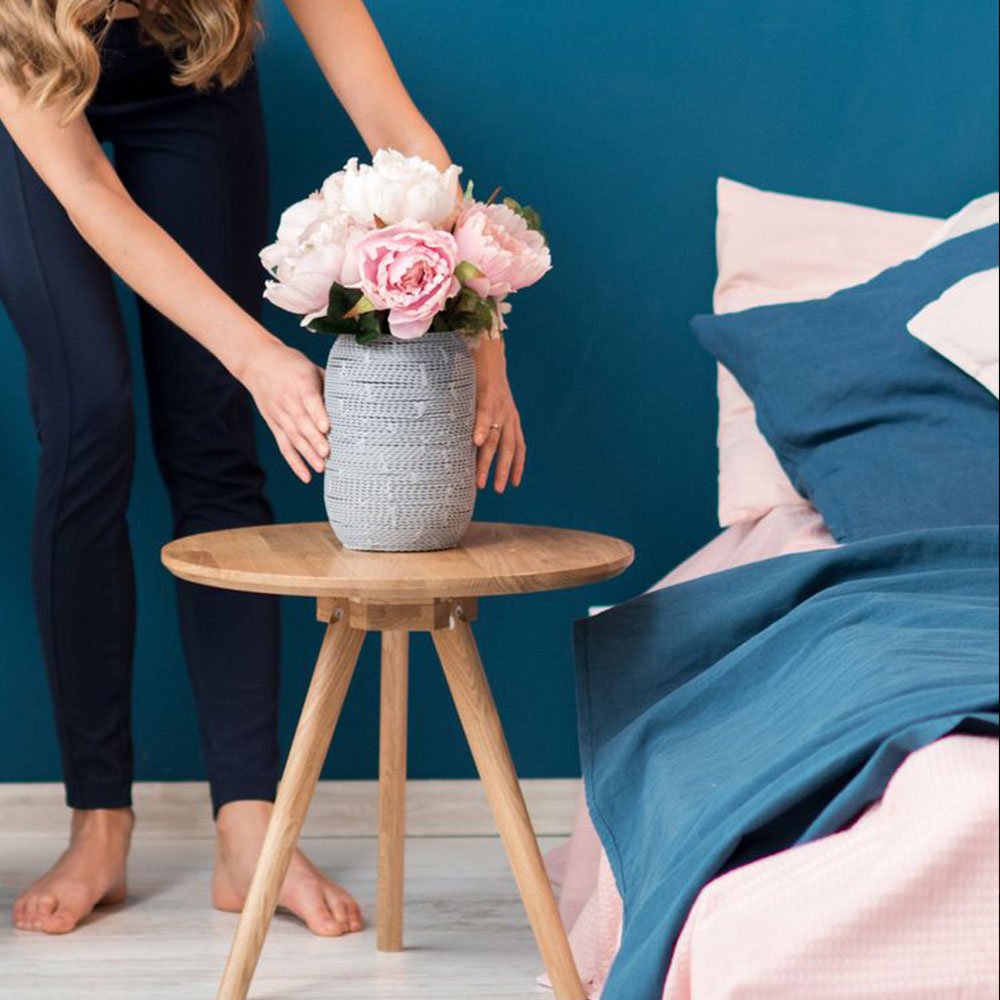 Woman decorating her bedroom with vase full of peony 