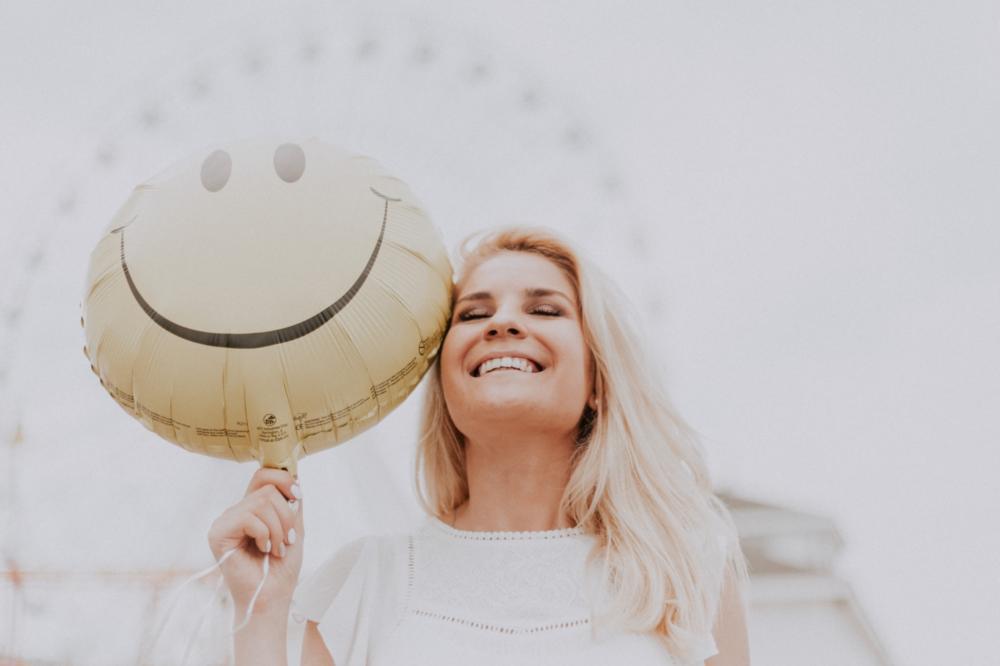 blonde woman with yellow "smiley" balloon