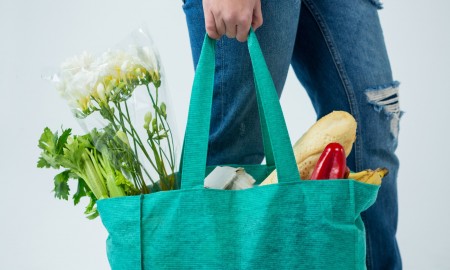 Woman with big textile bag full of vegetables, bread and flowers