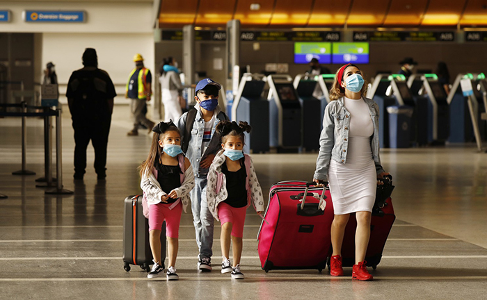 Vacation 2020 flying during coronavirus mother with three children wearing masks at the airport