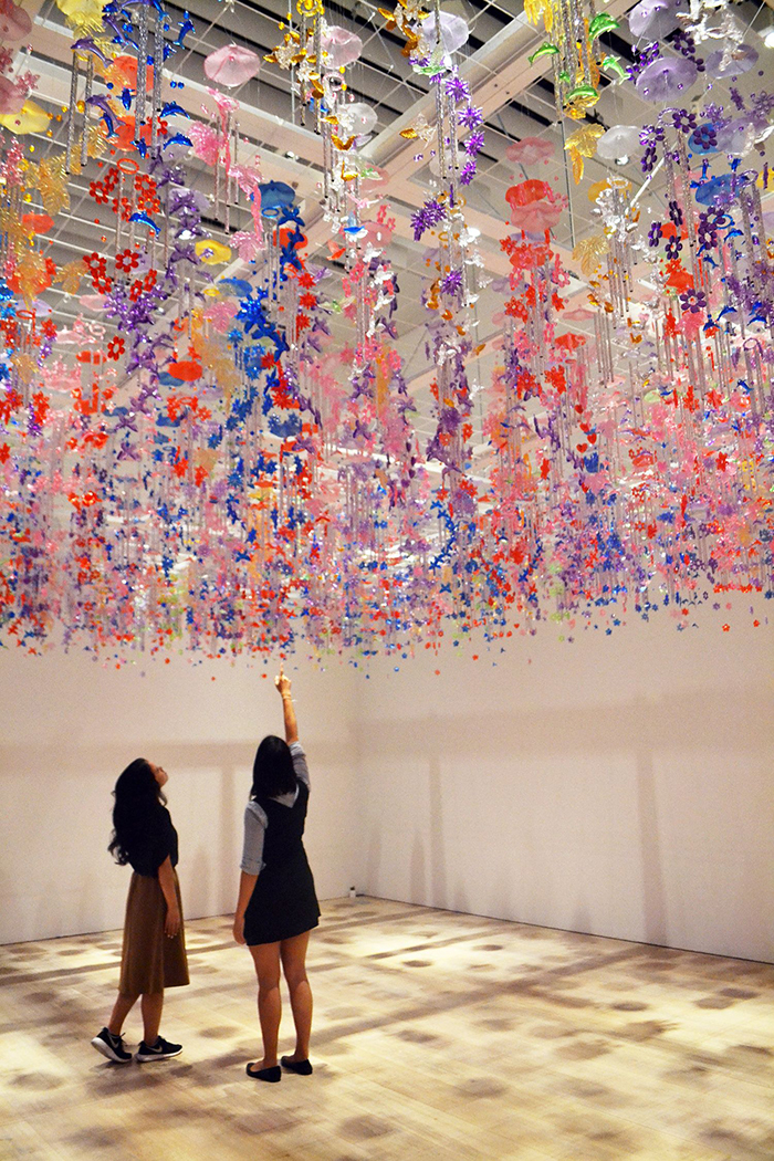 teamlab digital art exhibition two girls watching up in the mori art museum in a hall with flowers hanging from the ceiling