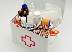 Open first aid box filled with medical supplies in white background