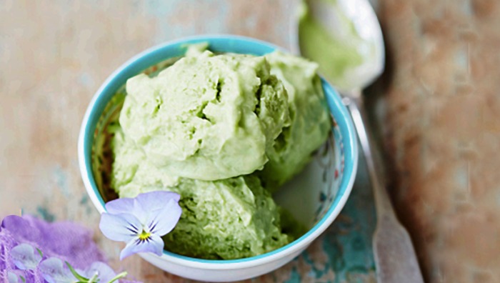 lactose free ice cream avocado green in a cup with a spoon and a flower decoration