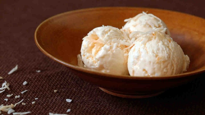 three balls of lactose free coconut ice cream in a brown bowl on a table