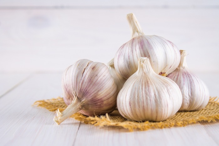 a small pile of garlic on a little burlap cloth white table top